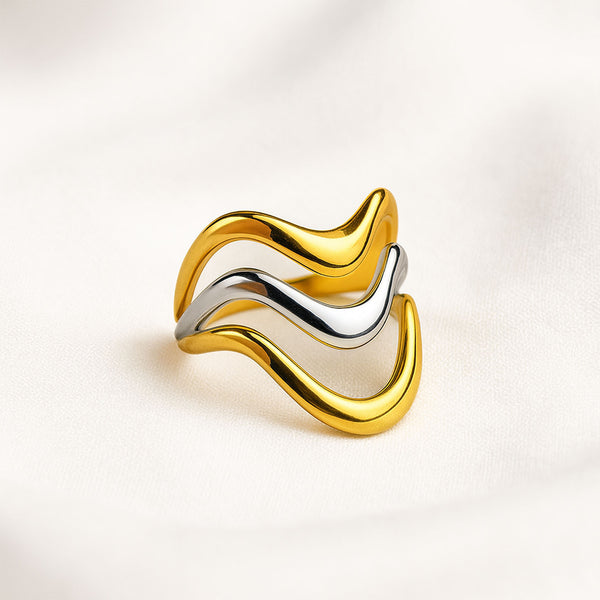 Gold and silver ring with wavy design on a light beige background